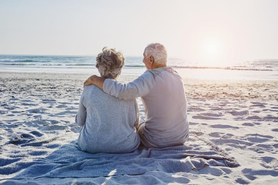 Senior couple sitting on the beach looking at distance