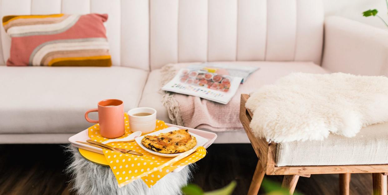 living room with pink velvet couch and coffee on fur ottoman