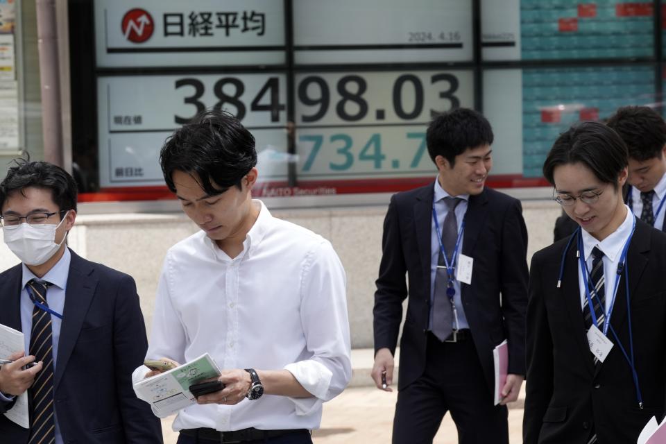 People walk near an electronic stock board showing Japan's Nikkei 225 index at a securities firm Tuesday, April 16, 2024, in Tokyo. (AP Photo/Eugene Hoshiko)