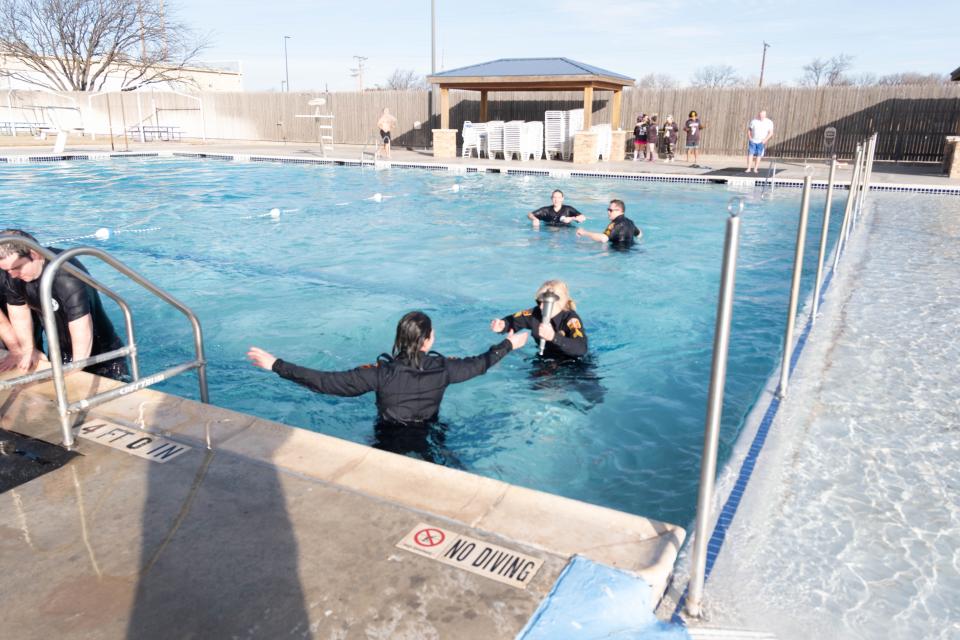 Sgt. Carla Burr carries the torch across the pool at the Polar Plunge Saturday morning at the Amarillo Town Club.
