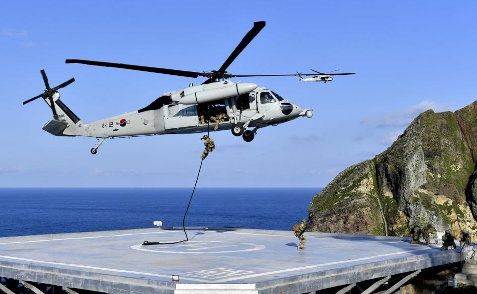 In this photo provided by South Korea's Navy, members of South Korean Navy's special forces rappel down from the UH-60 helicopter during the drill on the islets called Dokdo in Korean and Takeshima in Japanese, Sunday, Aug. 25, 2019. In a development that could possibly further complicate ties between Seoul and Tokyo, South Korea's navy on Sunday began two-day exercises on and around a group of islets controlled by South Korea but also claimed by Japan.(South Korea's Navy via AP)