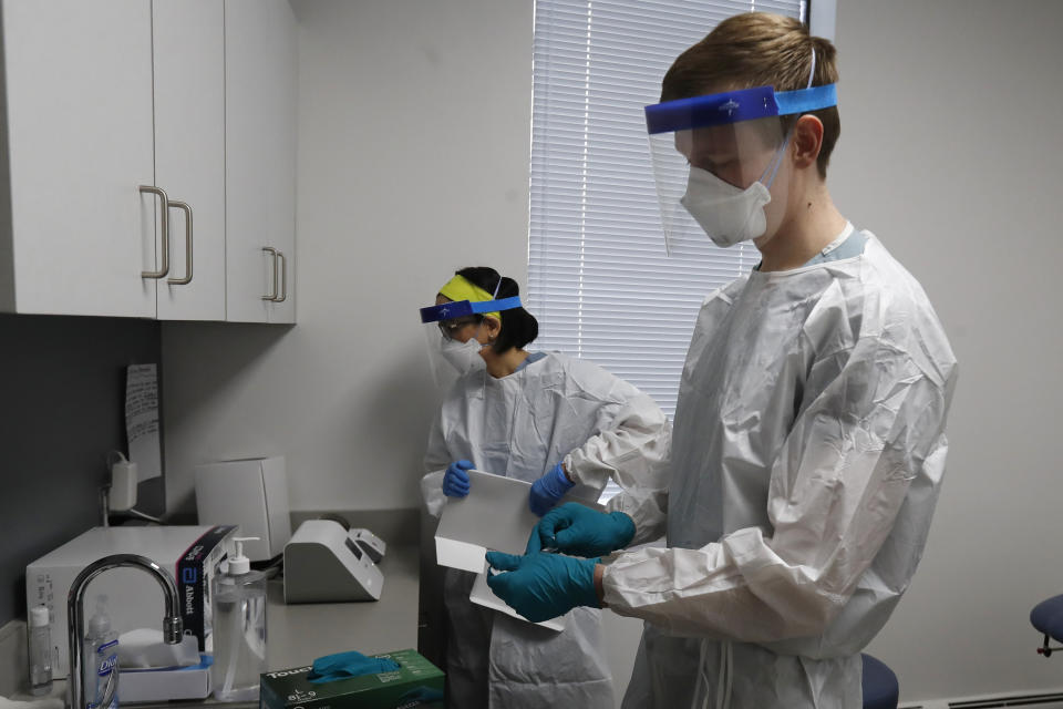 In this Friday, April 24, 2020 photo, Wayne State University medical school students Lucia Luna-Wong, left and Michael Moentmann work in a COVID-19 testing center in Detroit. The students are volunteering in one of America's hardest-hit cities, testing police officers, firefighters, bus drivers and other essential workers who keep Detroit running. (AP Photo/Carlos Osorio)