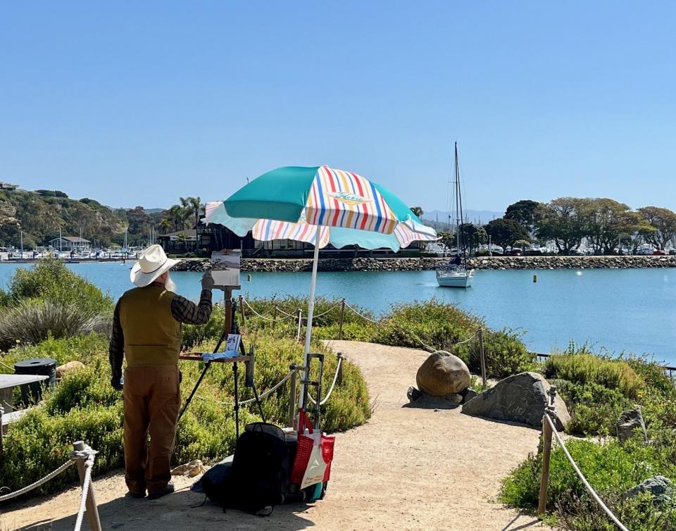 An artist paints a harbor scene of the Dana Point Boat Harbor.