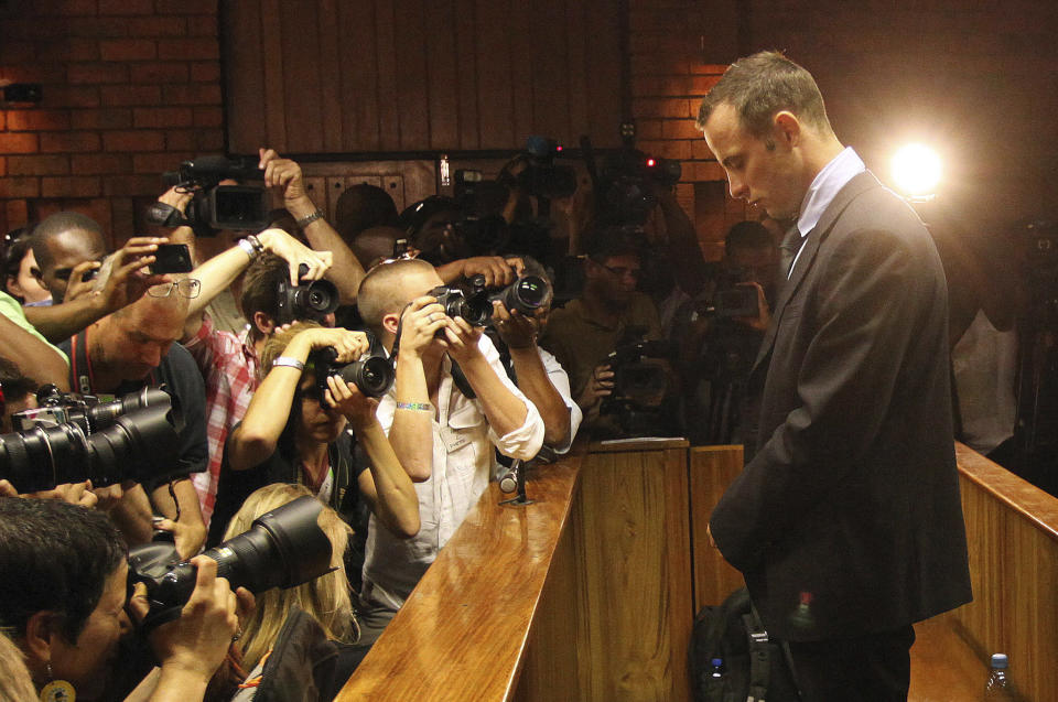 FILE - Photographers take photos of Olympic athlete Oscar Pistorius as he appears at a bail hearing for the shooting death of his girlfriend Reeva Steenkamp, in Pretoria, South Africa, Friday, Feb 20, 2013. Eight years after he shot dead his girlfriend, Pistorius is up for parole, but first he must meet with her parents as part of the parole procedure. A parole hearing for Pistorius was scheduled for last month and then canceled, partly because a meeting between Pistorius and Steenkamp's parents, Barry and June, had not been arranged, lawyers for both parties told The Associated Press on Monday, Nov. 8, 2021. (AP Photo/Themba Hadebe, File)