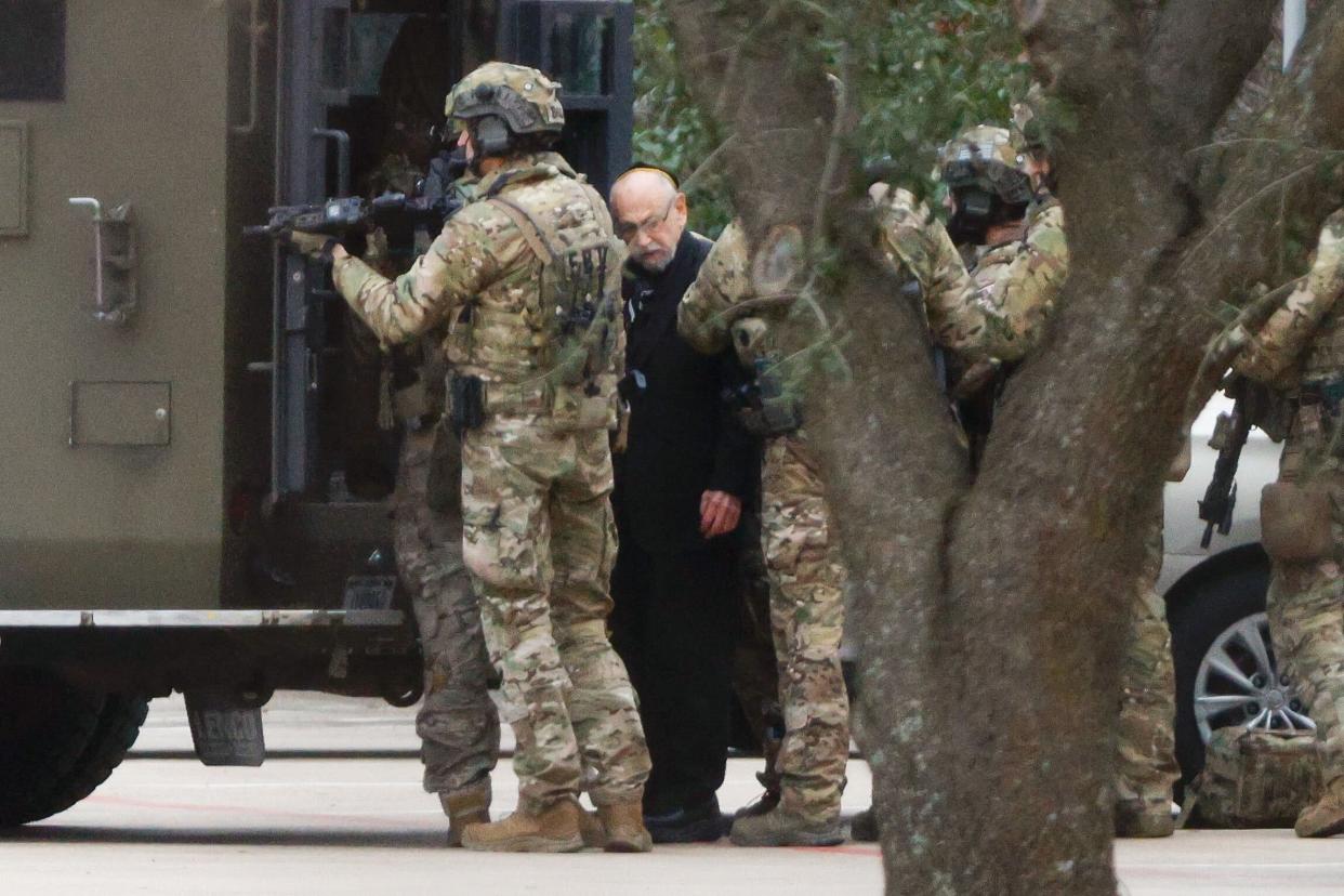 Shortly after 5 p.m., local time, authorities escort a hostage out of the Congregation Beth Israel synagogue in Colleyville, Texas, Saturday, Jan. 15, 2022. Police said the man was not hurt and would be reunited with his family.