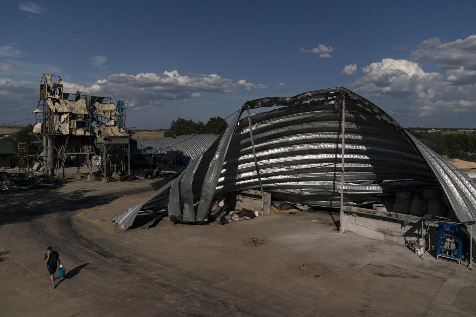 An employee walks near mangled warehouses at a grain facility in Pavlivka, Ukraine, Saturday, July 22, 2023, following Russian missile attacks. The collapse of the Black Sea grain deal and a series of missile strikes on Ukrainian grain silos and ports have left farmers with few options to export their grain — and all of them are getting more expensive. (AP Photo/Jae C. Hong)