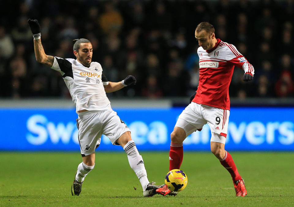 Fulham's Dimitar Berbatov, right, and Swansea City's Chico battle for the ball during their English Premier League soccer match at the Liberty Stadium, Swansea, Wales, Tuesday, Jan. 28, 2014. (AP Photo/Nick Potts, PA Wire) UNITED KINGDOM OUT - NO SALES - NO ARCHIVES