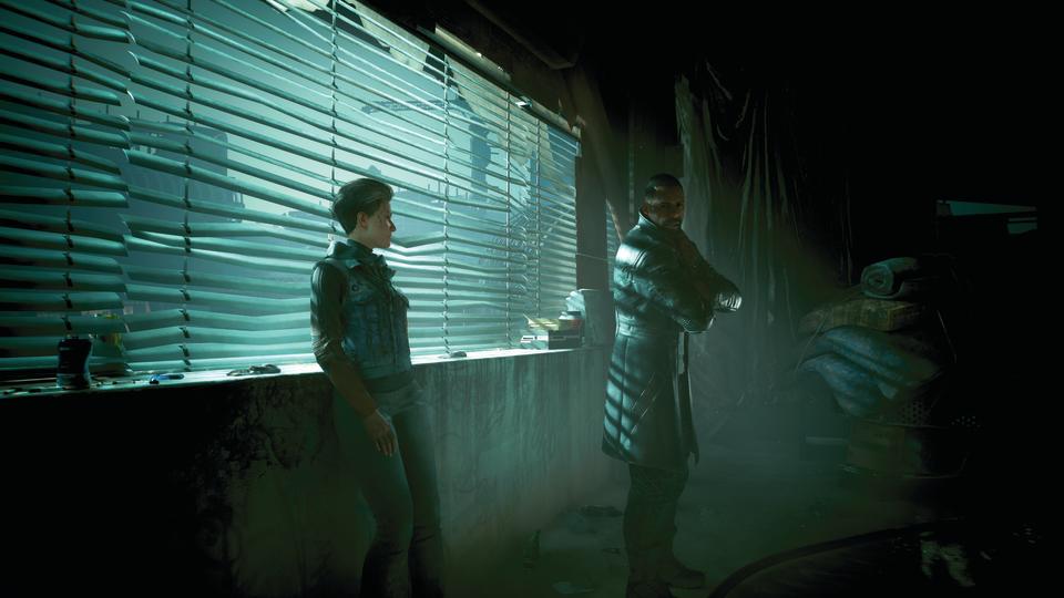 Solomon Reed and an NPC in a dark room with their backs to a window with blinds