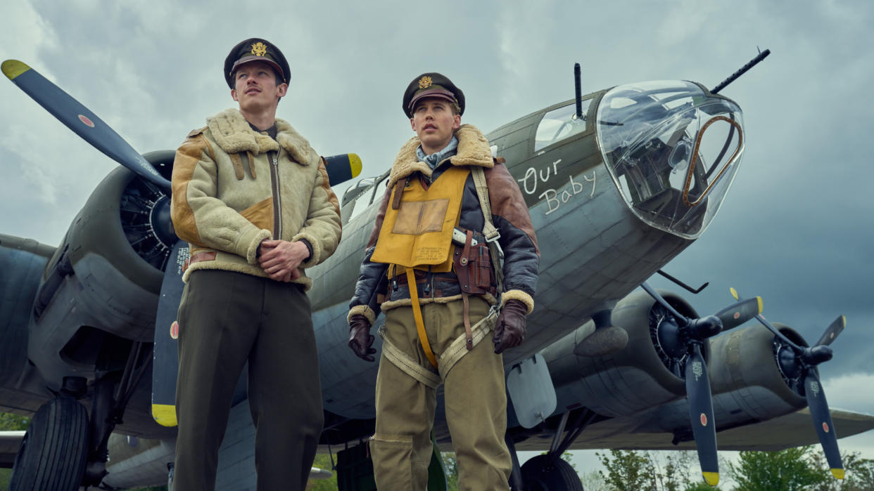  Callum Turner and Austin Butler in Masters of the Air, standing by a plane wearing pilots' uniform. 