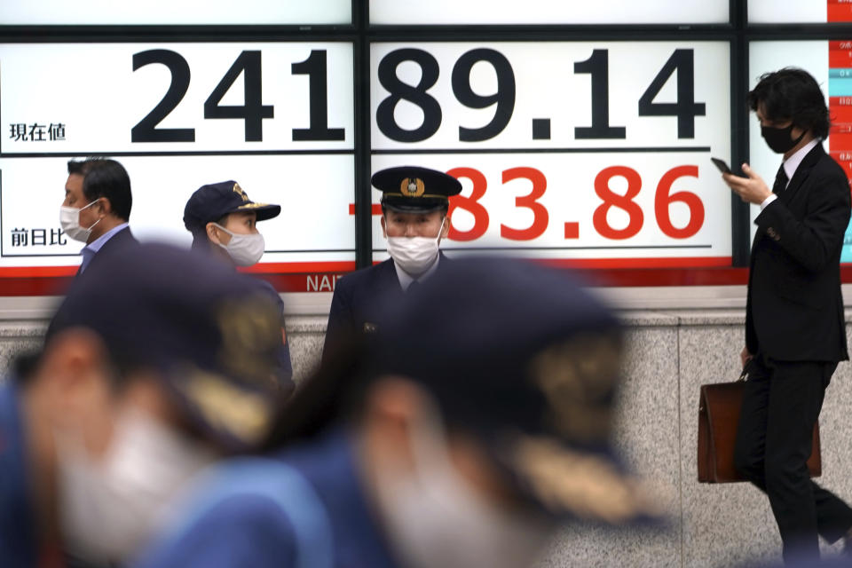 People wearing masks against the spread of the coronavirus walk past an electronic stock board showing Japan's Nikkei 225 index at a securities firm in Tokyo Friday, Nov. 6, 2020. Asian stock markets were mixed Friday after Wall Street rose amid protracted vote-counting following this week's U.S. elections. (AP Photo/Eugene Hoshiko)