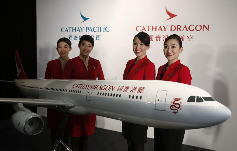 FILE - In this Jan. 28, 2016, file photo, flight attendants pose next to a model jet decorated in the new livery of Hong Kong airline Cathay Dragon, formerly known as Dragonair in Hong Kong. Cathay Pacific Airways said Wednesday, March 9, 2016, that its annual profit nearly doubled in 2015 as passenger demand grew and tumbling oil prices cut its fuel bill. Hong Kong’s biggest airline said that net income jumped 90.5 percent from the year before to 6 billion Hong Kong dollars ($773 million). (AP Photo/Kin Cheung, File)