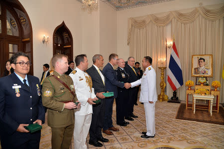 Richard Harris, Australian member of the Thai cave rescue team shakes hands with Thailand's Prime Minister Prayuth Chan-ocha, next to Craig Challen after receiving the Member of the Most Admirable Order of the Direkgunabhorn award at the Government House in Bangkok, Thailand, April 19, 2019. Thailand Government House/Handout via REUTERS