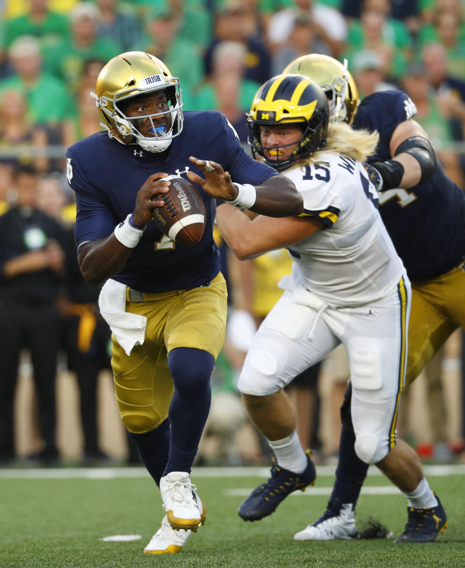 Notre Dame quarterback Brandon Wimbush (7) is chased out of the pocket by Michigan defensive lineman Chase Winovich (15) in the first half of an NCAA football game in South Bend, Ind., Saturday, Sept. 1, 2018. (AP Photo/Paul Sancya)