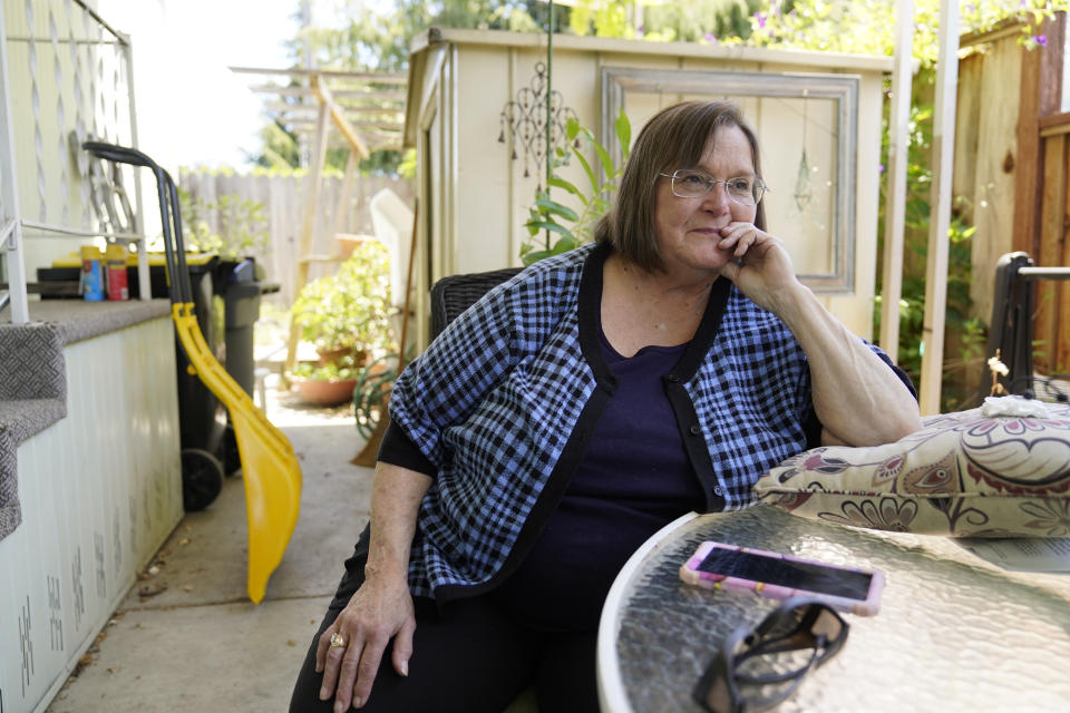 In this June 29, 2021, photo, Judy Pavlick, 74, poses outside where she lives at a mobile home park in Sunnyvale, Calif. Newly retired, Pavlick was among hundreds of seniors who enjoyed the low cost-of-living and friendly atmosphere at Plaza Del Rey, a sprawling mobile home park in Sunnyvale. Then the Carlyle Group acquired the property and things began to change. Pavlick's rent surged by more than 7%. Additional increases followed. She said the unexpected jump forced her and her neighbors, many on fixed incomes and unable to relocate, to sometimes choose between food and medicine. (AP Photo/Eric Risberg)