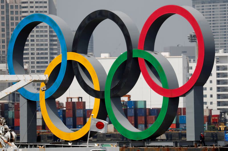 FILE PHOTO: The giant Olympic rings are seen behind Japan's national flag at the waterfront area at Odaiba Marine Park in Tokyo