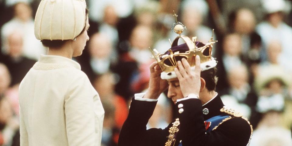 <p>Kneeling before Queen Elizabeth II as she crowns him Prince of Wales at the investiture with a gold crown.</p>