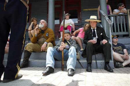 Civil War re-enactors Ray Wetzel (L-R), 62, a bounty hunter, Jordan Gibson, 13, a Confederate infantryman in the 33rd Virginia, Company C, and Bob Bosler, 59, as Jefferson Davis, along with other spectators line the streets before the Gettysburg Memorial Day parade in Gettysburg, Pennsylvania, May 26, 2014. REUTERS/Mark Makela