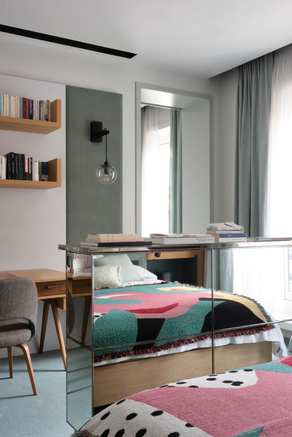 In the master bedroom, the bed features a large custom-made headboard draped in a lime green fabric and a woven Slowdown Studio bedspread, as well as light oak and lacquered wood paneling.