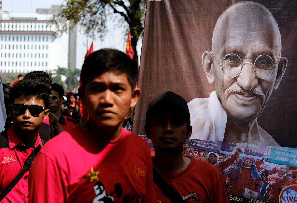 Workers stand near an image of Mahatma Gandhi