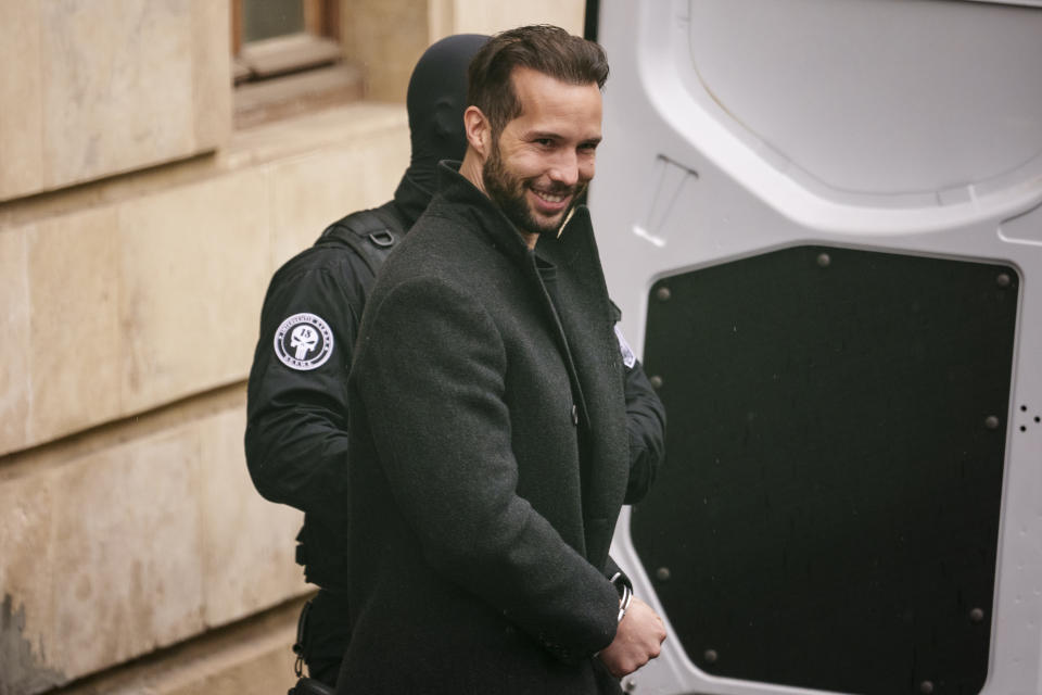 A police officer escorts Tristan Tate into a police van outside the Court of Appeal in Bucharest, Romania, Tuesday, March 12, 2024. Online influencer Andrew Tate was detained in Romania and handed an arrest warrant issued by British authorities, his spokesperson said Tuesday. (AP Photo/Andreea Alexandru)