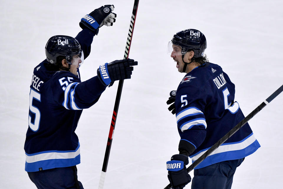 Winnipeg Jets' Brenden Dillon (5) celebrates his goal with Mark Scheifele (55) during the third period of an NHL hockey match against the Dallas Stars in Winnipeg, Manitoba, on Saturday, Nov. 11, 2023. (Fred Greenslade/The Canadian Press via AP)