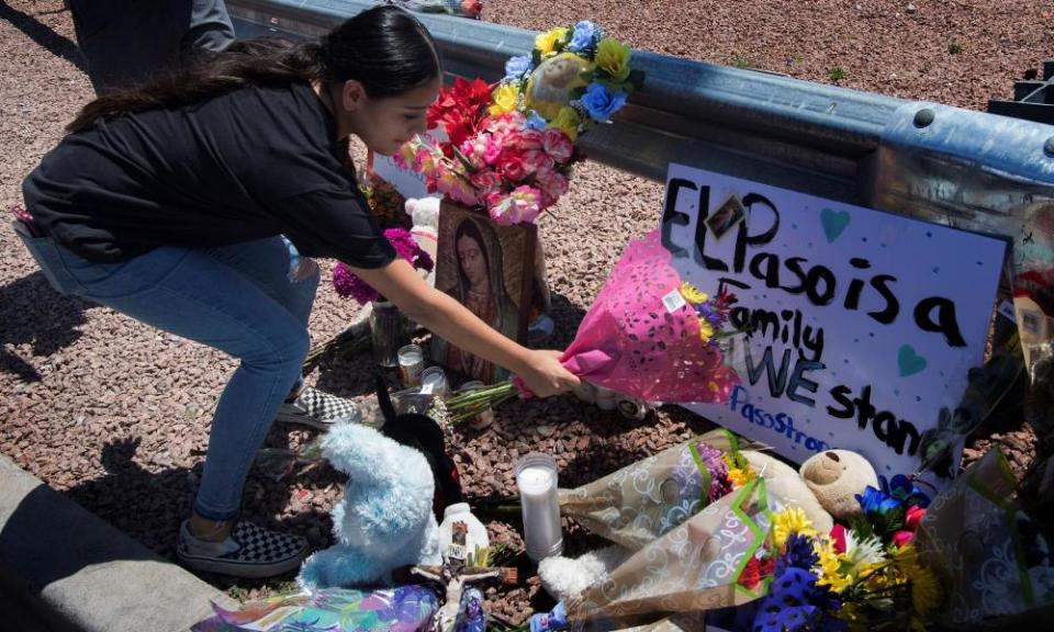 A woman places flowers beside a makeshift memorial outside the Walmart.