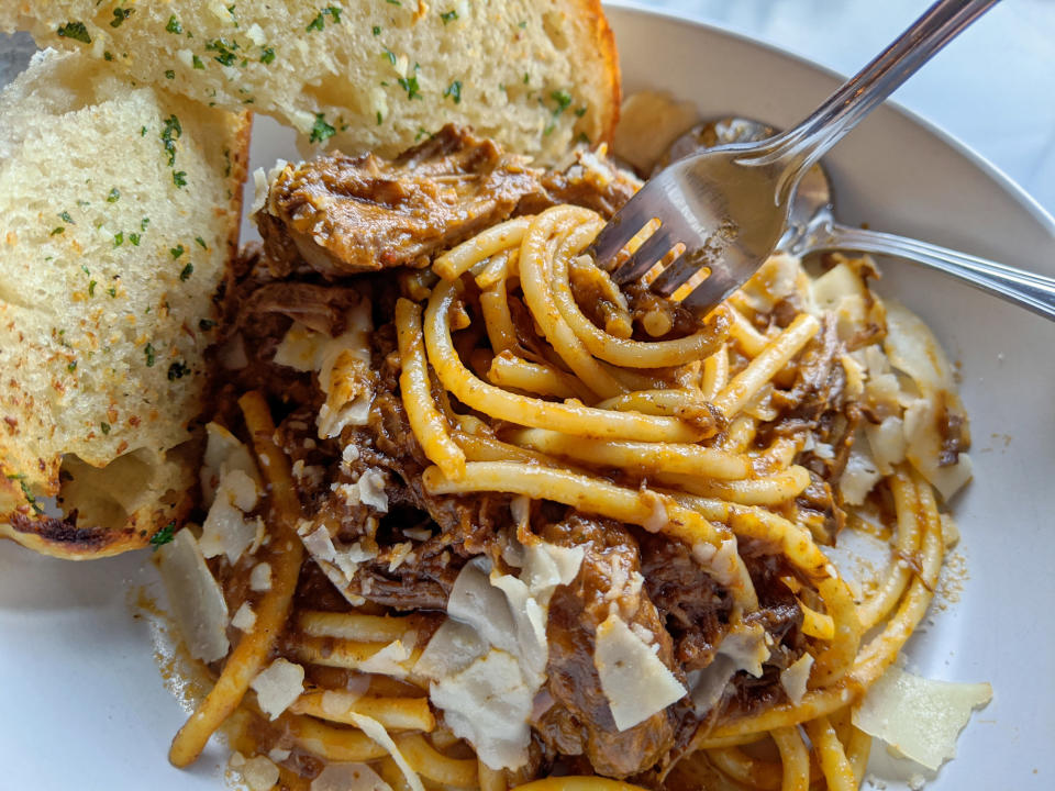 Bowl of pasta with short ribs and garlic toast.