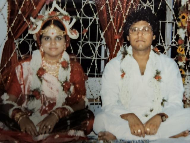 Sonali Chandra's parents - who had an arranged marriage - sit, cross-legged, on a cushion. They are both wearing traditional Indian clothing.