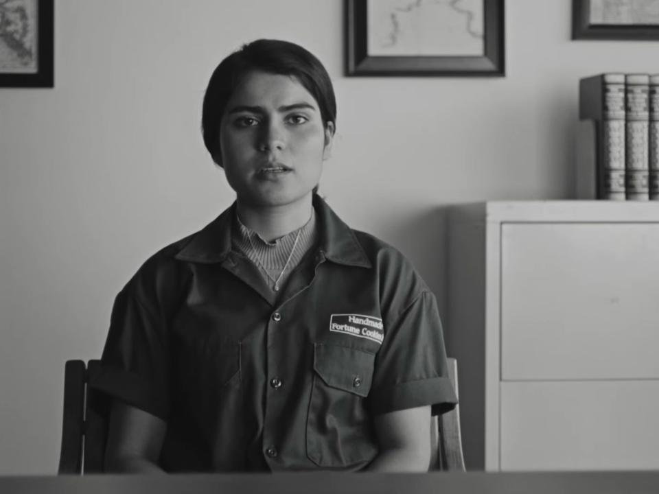 donya sitting in front of a desk in an office wearing a factory coverall uniform in fremont