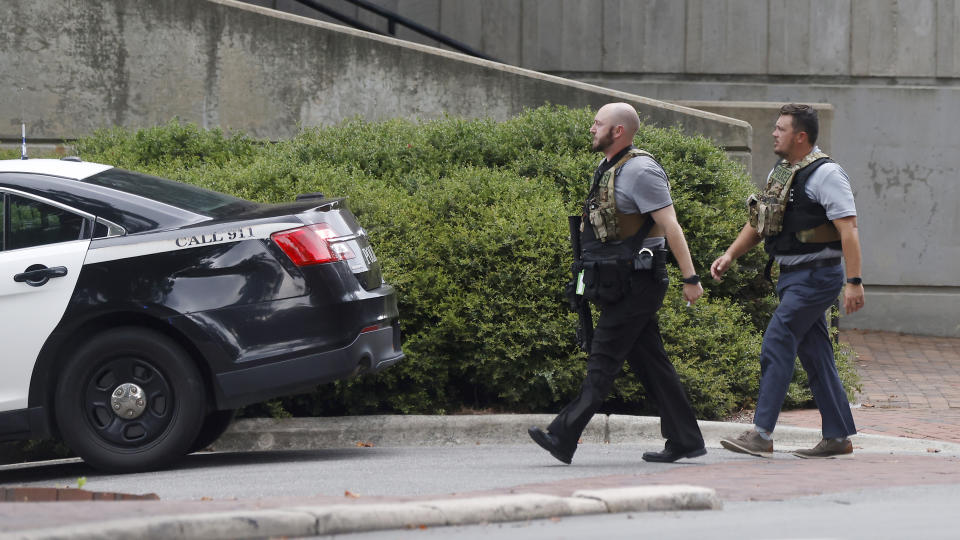 Two police officers move around a building on the University of North Carolina at Chapel Hill campus in Chapel Hill, N.C., on Monday, Aug. 28, 2023, after a report of an "armed and dangerous person" on campus. (Kaitlin McKeown/The News & Observer via AP)