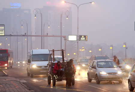 Vehicles and pedestrians are seen during evening fog and air pollution covering Skopje, Macedonia December 14, 2017. REUTERS/Ognen Teofilovski