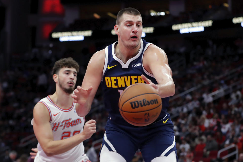 Denver Nuggets center Nikola Jokic, right, loses the ball on a pass in front of Houston Rockets center Alperen Sengun, left, during the first half of an NBA basketball In-Season Tournament game Friday, Nov. 24, 2023, in Houston. (AP Photo/Michael Wyke)