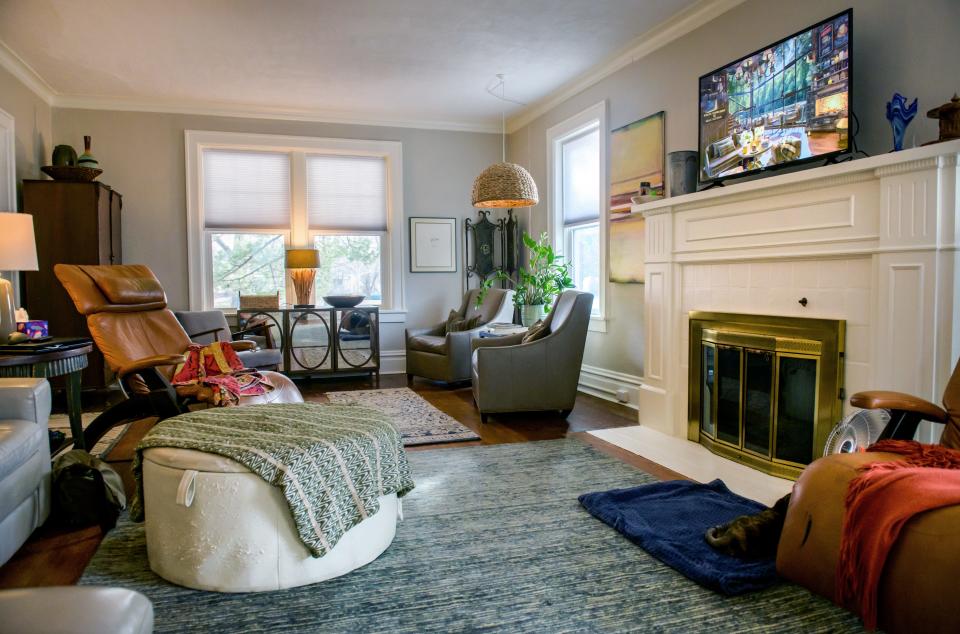 The main living room features a fireplace and mantle and plenty of sunlight through a set of large windows.