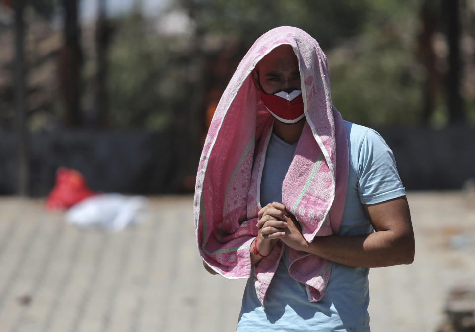 A relative of a person who died of COVID-19 reacts during cremation in Jammu, India, Monday, May 24, 2021. India crossed another grim milestone Monday of more than 300,000 people lost to the coronavirus as a devastating surge of infections appeared to be easing in big cities but was swamping the poorer countryside. (AP Photo/Channi Anand)