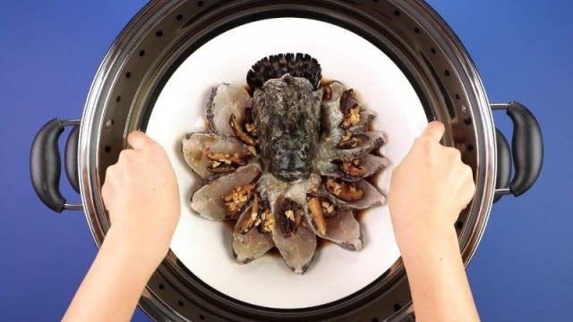 Placing grouper fish dish into a steamer