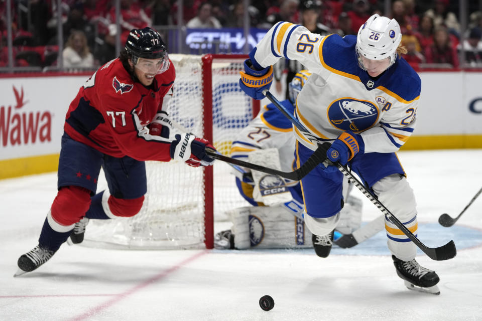 Washington Capitals right wing T.J. Oshie (77) and Buffalo Sabres defenseman Rasmus Dahlin (26) battle for control of the puck in the first period of an NHL hockey game, Wednesday, Nov. 22, 2023, in Washington. (AP Photo/Mark Schiefelbein)