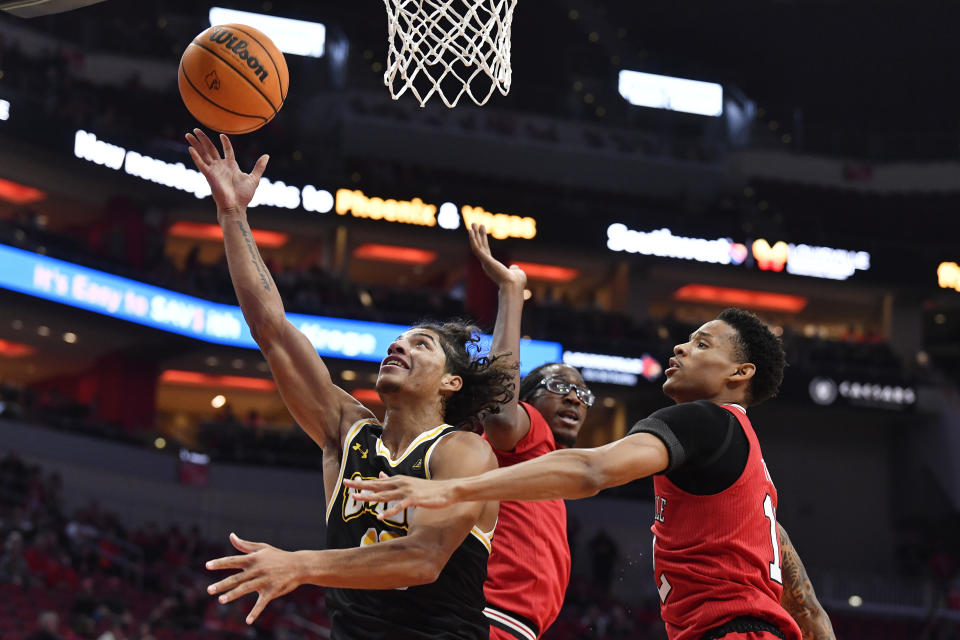 Maryland Baltimore County guard Dion Brown (13) attempts a shot past the defense of Louisville forward JJ Traynor (12), right, and center Dennis Evans (11) during the first half of an NCAA college basketball game in Louisville, Ky., Monday, Nov. 6, 2023. (AP Photo/Timothy D. Easley)