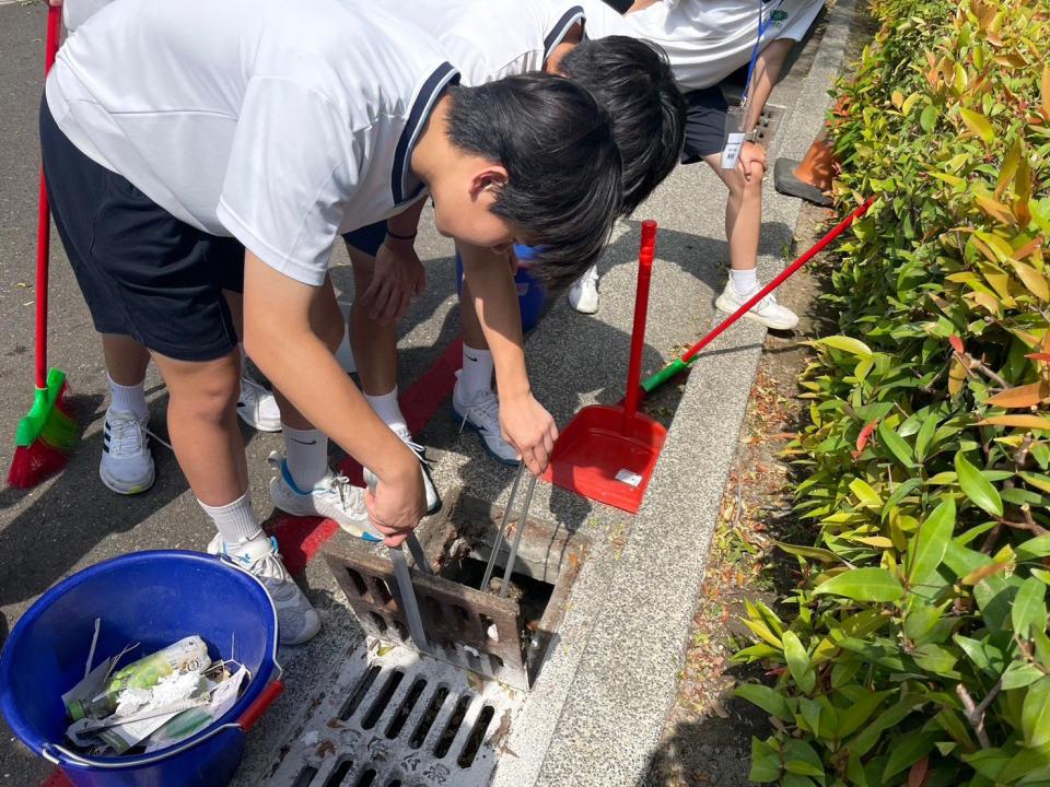 同學仔細地打開水溝蓋進行清掃。