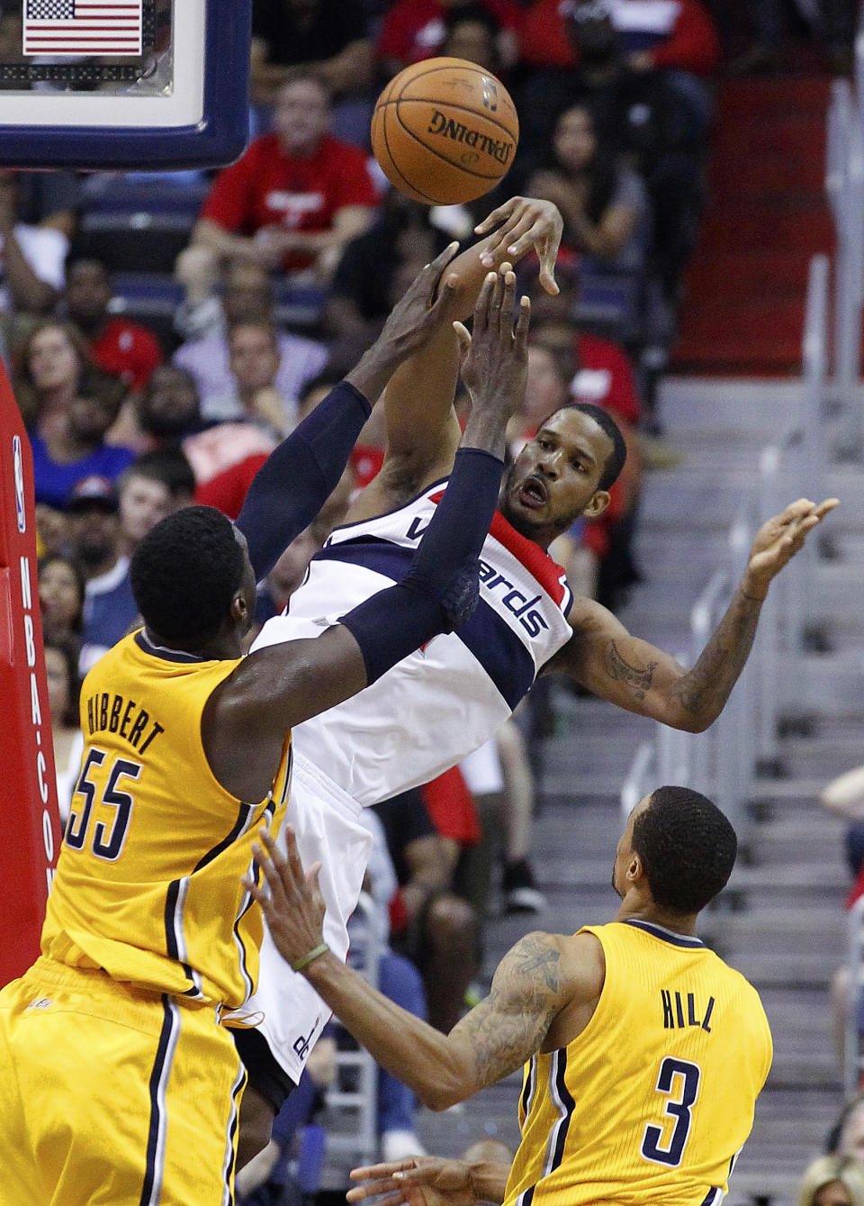 Washington Wizards forward Trevor Ariza (1) passes over Indiana Pacers center Roy Hibbert (55) and Indiana Pacers guard George Hill (3) during the second half of Game 4 of an Eastern Conference semifinal NBA basketball playoff game in Washington, Sunday, May 11, 2014. (AP Photo/Alex Brandon)