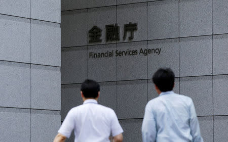Men walk toward a sign of Japan's Financial Services Agency in Tokyo August 7, 2014. REUTERS/Toru Hanai/File Photo