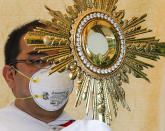 A Catholic priest wearing a protective mask holds a Monstrance with the Sacred Host as he rides a pick-up truck around villages during a new Palm Sunday ritual to help prevent the spread of the new coronavirus in Manila, Philippines on Sunday, April 5, 2020. Catholic devotees usually troop to churches on Palm Sunday to have their palm fronds blessed to commemorate the entry of Jesus Christ into Jerusalem. The new coronavirus causes mild or moderate symptoms for most people, but for some, especially older adults and people with existing health problems, it can cause more severe illness or death. (AP Photo/Aaron Favila)