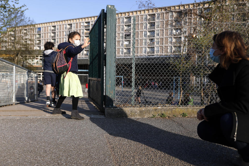 FILE - In this Thursday, April 1, 2021 file photo, Emma Woodroof waves goodbye to her mother Julie as she enters her school in Strasbourg, eastern France. Children, parents and teachers are battling with connection problems across France after an abrupt nationwide switch to online learning saturated networks and embarrassed the government. Paris prosecutors opened an investigation into possible hacking into key systems, the prosecutor’s office said Wednesday, April 7. (AP Photo/Jean-Francois Badias)