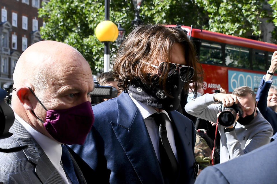 Johnny Depp, right, wearing a protective mask arrives at the Royal Court of Justice, in London, Tuesday, July 7, 2020. Johnny Depp is suing a tabloid newspaper for libel over an article that branded him a "wife beater." On Tuesday, a judge at the High Court is due to begin hearing Depp's claim against The Sun's publisher, News Group Newspapers, and its executive editor, Dan Wootton, over the 2018 story alleging he was violent and abusive to then-wife Amber Heard. Depp strongly denies the claim. (AP Photo/Alberto Pezzali)