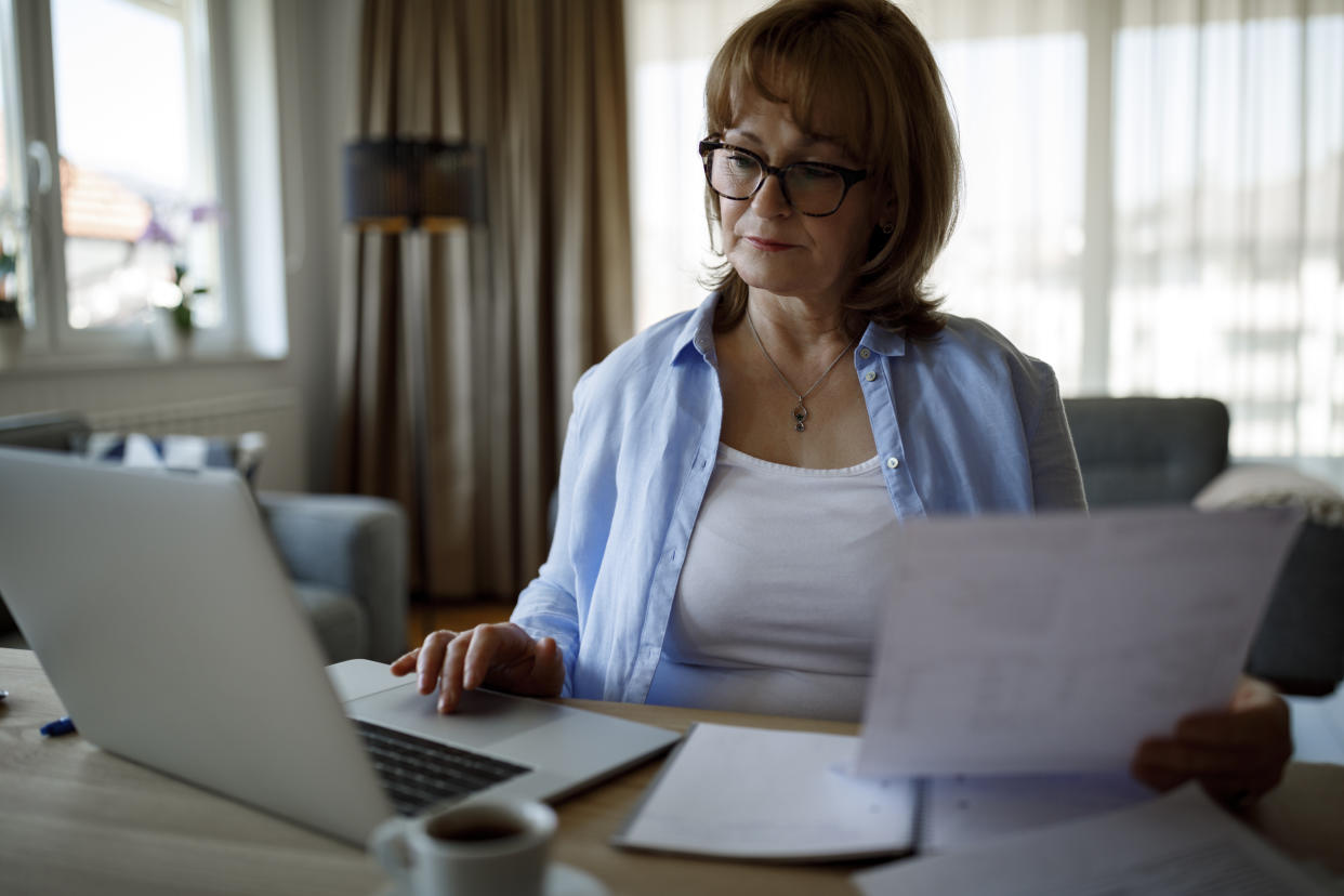 Woman on laptop reading papers