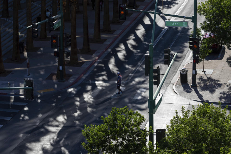 A man crosses to the shady side of the street on Thursday, June 29, 2023, in Las Vegas. Smoky haze, hot weather and powerful storms brought dangerous and uncomfortable conditions to parts of the U.S. heading into a long July Fourth weekend that typically draws Americans to outdoor gatherings. (AP Photo/Ty O'Neil)