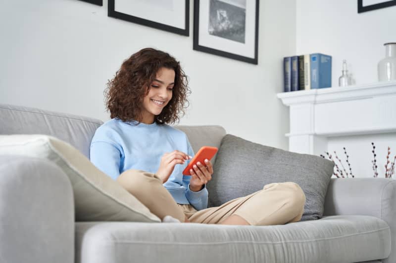 Happy girl holding cell phone using smartphone device at home