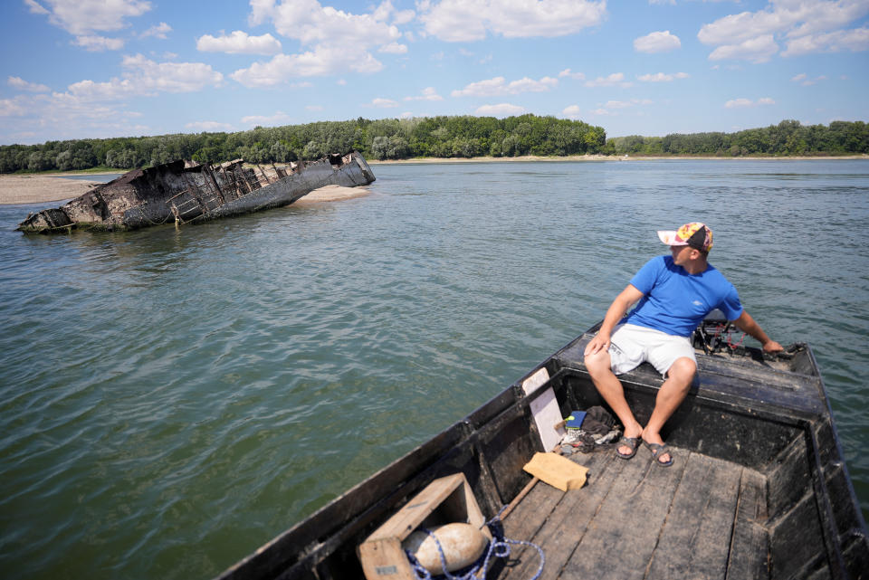 Ivica Skodric, a 37-year old local fisherman, sails on his boat passing by the wreckage of a World War Two German warship in the Danube in Prahovo, Serbia August 18, 2022. REUTERS/Fedja Grulovic