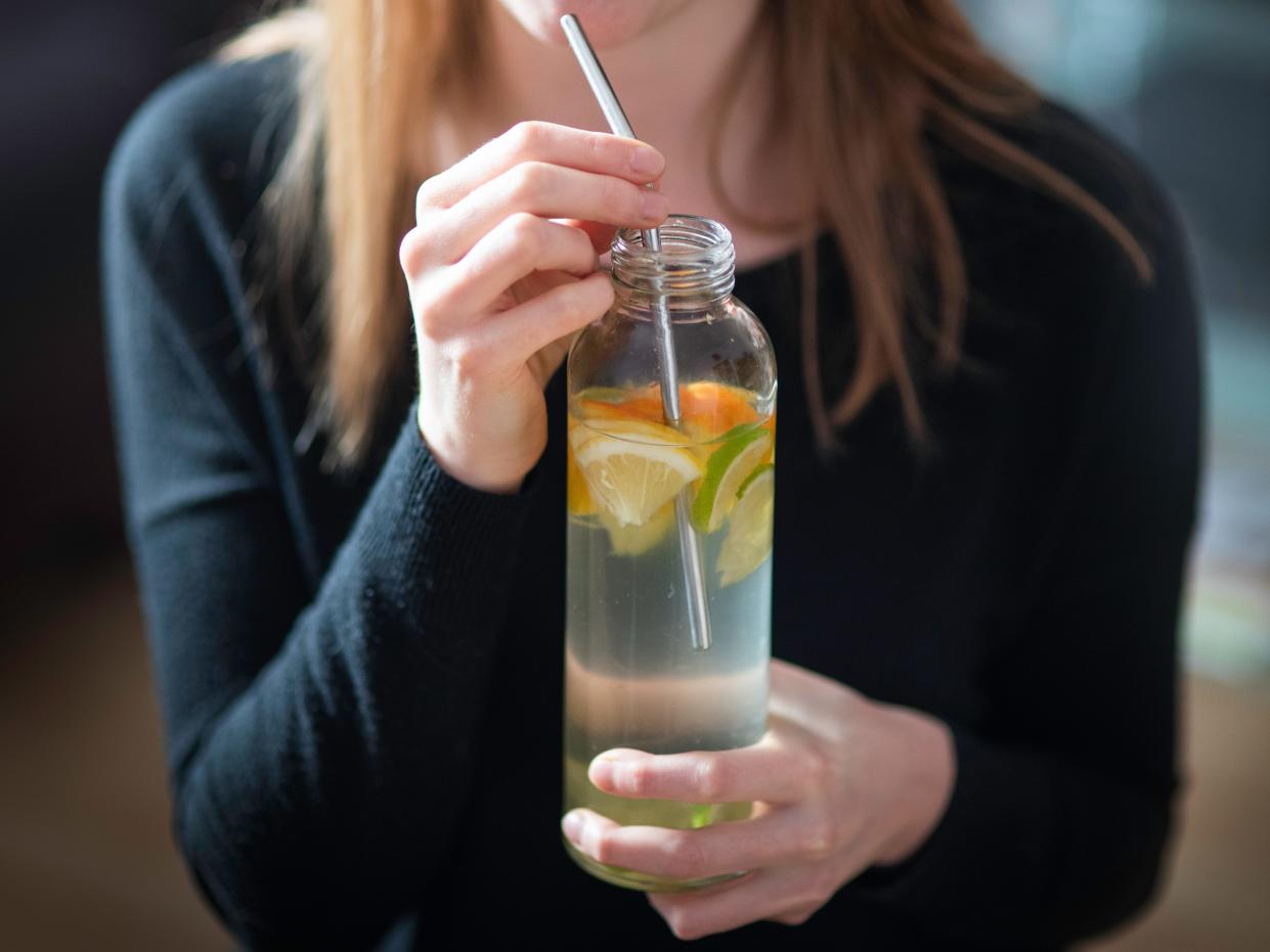 A picture of a woman drinking from a reusable bottle.