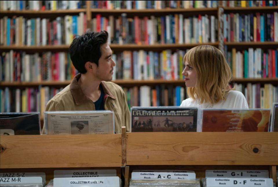 Lucy Boynton and Justin Min look at each other in a record shop in a still from 'The Greatest Hits'