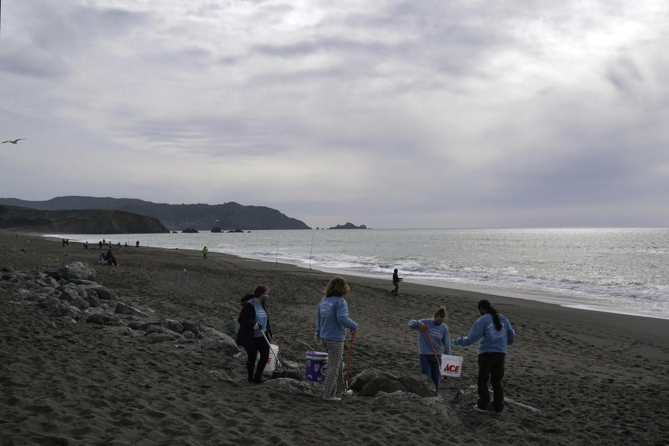Pacifica Beach Coalition volunteers Iona Pratt-Bauman, from left, Anneliese Phillips, Sophia Woehl and Amaelia Bringas, all 16, pick up trash off Sharp Park Beach in Pacifica, Calif., Wednesday, March 17, 2021. Disposable masks, gloves and other personal protective equipment have safeguarded untold lives during the pandemic. They’re also creating a worldwide environmental problem, littering streets and sending an influx of harmful plastic into landfills and oceans. (AP Photo/Jeff Chiu)